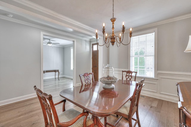 dining space with a wainscoted wall, a notable chandelier, a decorative wall, ornamental molding, and wood finished floors