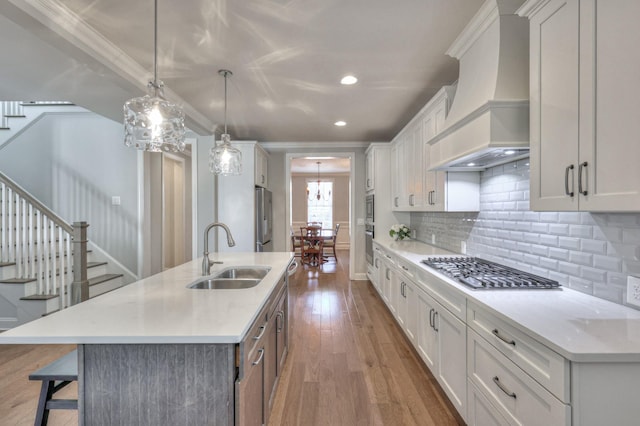 kitchen featuring a breakfast bar area, wood finished floors, a sink, appliances with stainless steel finishes, and custom exhaust hood