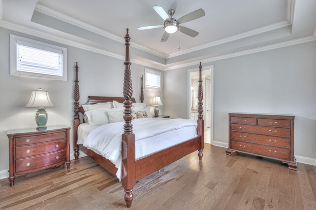 bedroom featuring a tray ceiling, wood finished floors, and ornamental molding