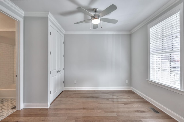 empty room featuring ornamental molding, baseboards, visible vents, and light wood finished floors