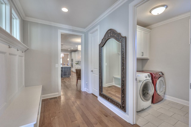 washroom featuring light wood-style floors, cabinet space, crown molding, and washer and clothes dryer