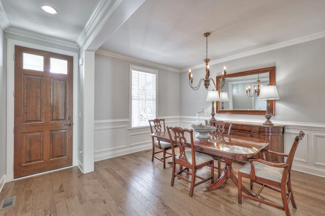 dining area with a notable chandelier, visible vents, wood finished floors, and ornamental molding