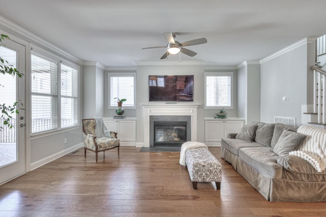 living area with crown molding, wood finished floors, and a fireplace with flush hearth