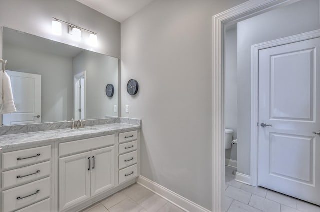 bathroom featuring toilet, baseboards, and vanity