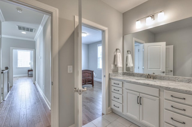 bathroom with wood finished floors, vanity, visible vents, baseboards, and ornamental molding