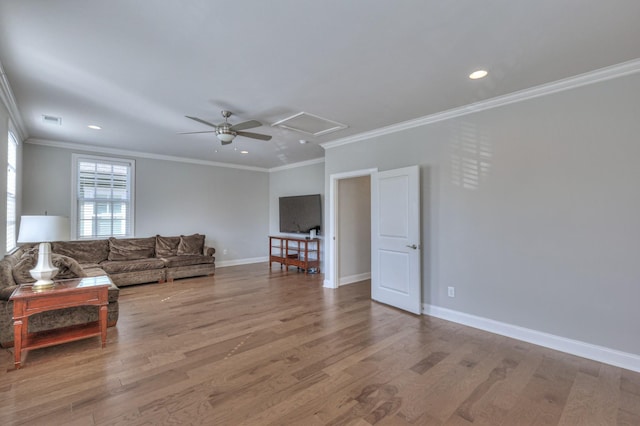 living area with visible vents, baseboards, light wood finished floors, attic access, and crown molding