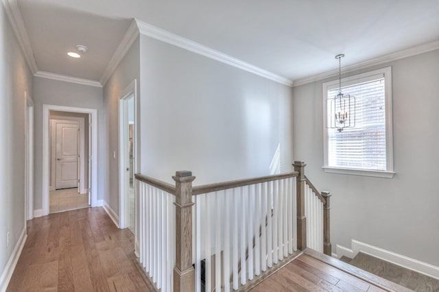 corridor featuring ornamental molding, baseboards, an upstairs landing, and wood finished floors