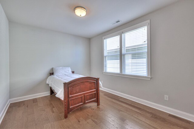 bedroom featuring wood finished floors, visible vents, and baseboards