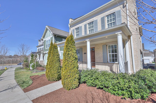 view of front of property featuring covered porch, central AC, and brick siding