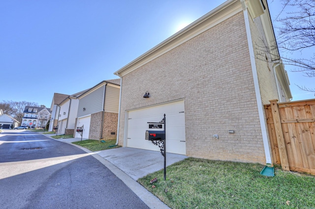 view of property exterior featuring a residential view, concrete driveway, brick siding, and fence