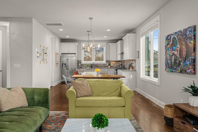 living area with dark wood-style flooring, recessed lighting, visible vents, a chandelier, and baseboards