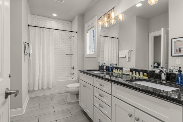 bathroom with toilet, double vanity, shower / bath combo with shower curtain, and a sink