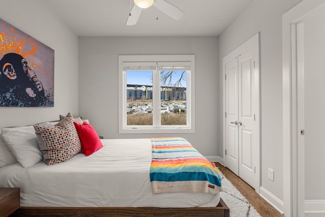 bedroom with a closet, wood finished floors, a ceiling fan, and baseboards