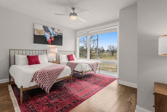 bedroom with ceiling fan, wood finished floors, and baseboards