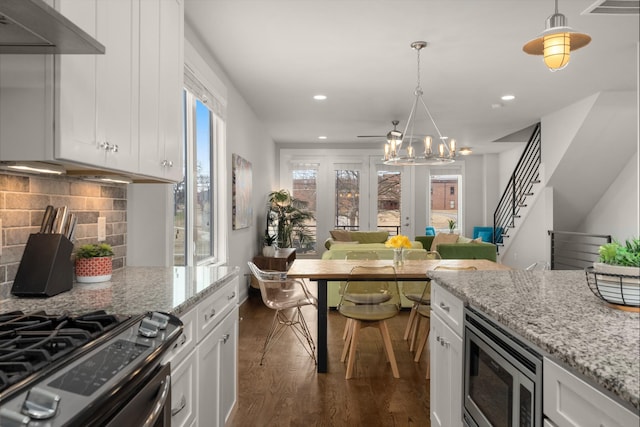 kitchen with white cabinets, light stone counters, stainless steel appliances, and decorative light fixtures