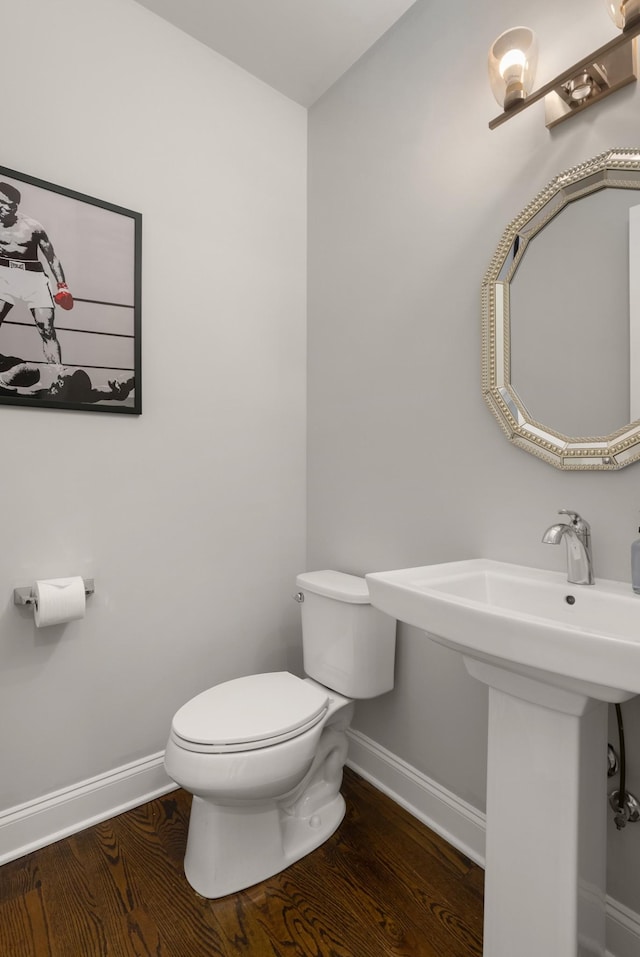 half bath featuring toilet, baseboards, and wood finished floors