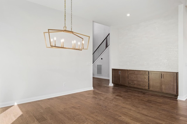 unfurnished room with dark wood-style flooring, visible vents, and baseboards