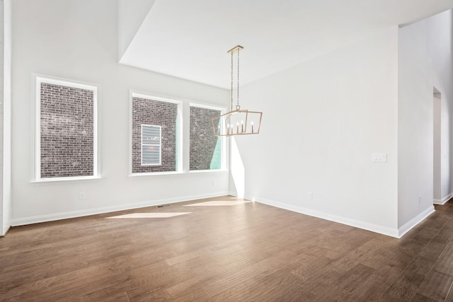 empty room with dark wood-style floors, baseboards, and a chandelier