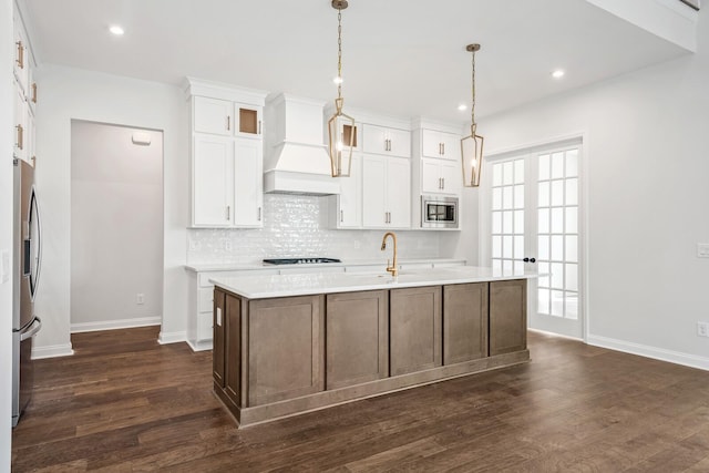 kitchen featuring a kitchen island with sink, custom range hood, appliances with stainless steel finishes, and light countertops