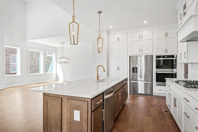 kitchen featuring light countertops, appliances with stainless steel finishes, a kitchen island with sink, and white cabinetry