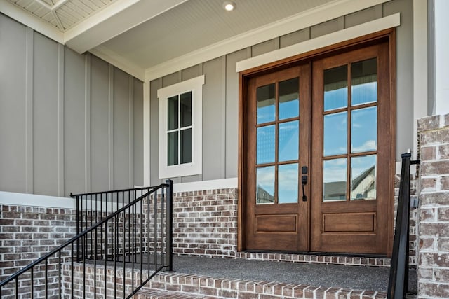 view of exterior entry featuring brick siding, board and batten siding, and french doors