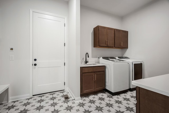 clothes washing area featuring light floors, cabinet space, a sink, washer and dryer, and baseboards