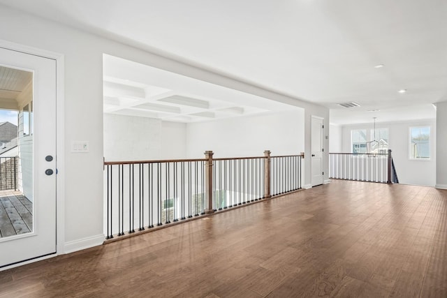 empty room with visible vents, coffered ceiling, wood finished floors, and beamed ceiling