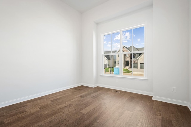 unfurnished room with dark wood finished floors, visible vents, and baseboards