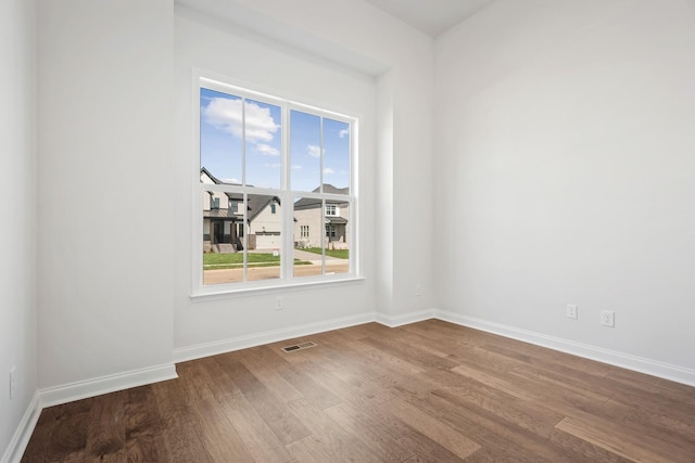 spare room with baseboards, visible vents, and wood finished floors