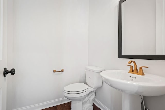 bathroom with a sink, toilet, baseboards, and wood finished floors