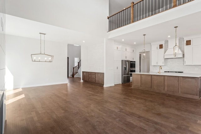 kitchen featuring light countertops, custom range hood, glass insert cabinets, white cabinets, and an island with sink