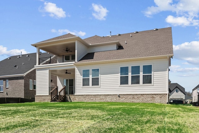 back of property featuring a balcony, brick siding, a ceiling fan, and a yard