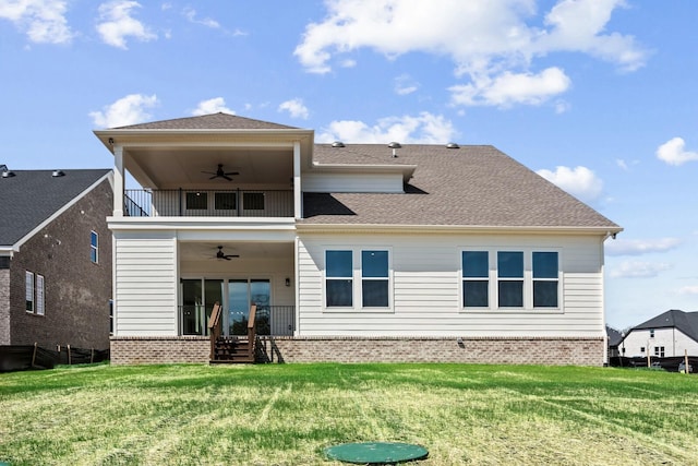 rear view of house featuring roof with shingles, a yard, brick siding, a ceiling fan, and a balcony