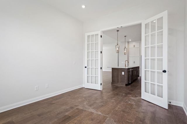 unfurnished room with french doors, dark wood-style flooring, a sink, and baseboards