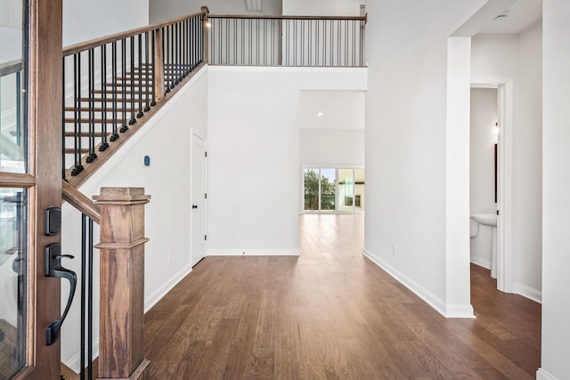 interior space featuring stairway, a high ceiling, baseboards, and dark wood-type flooring