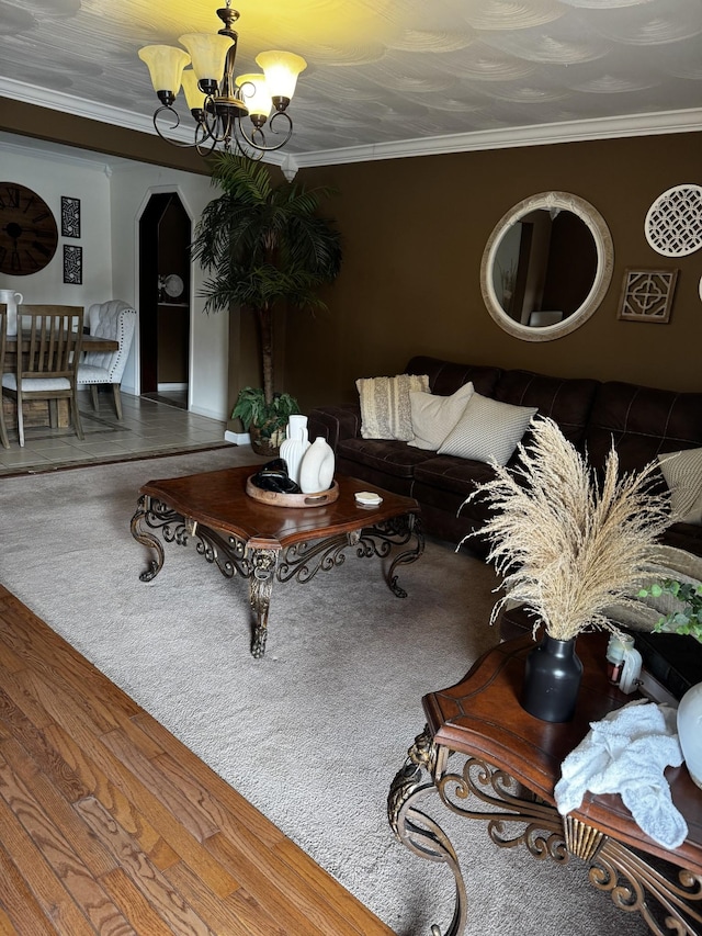 living area featuring arched walkways, wood finished floors, crown molding, and an inviting chandelier