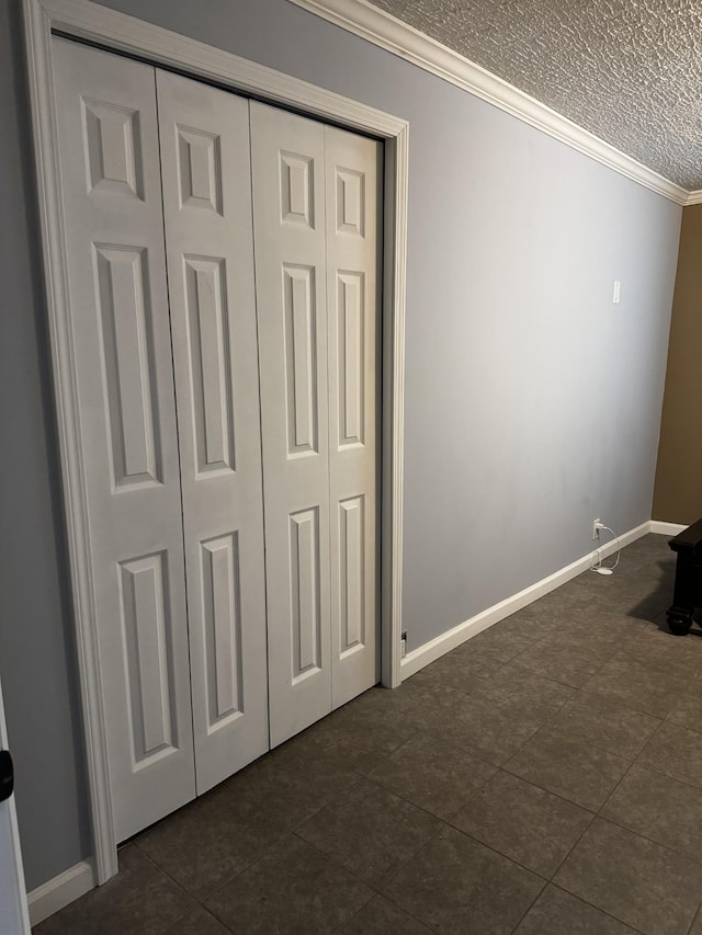 unfurnished bedroom with baseboards, a textured ceiling, a closet, and crown molding