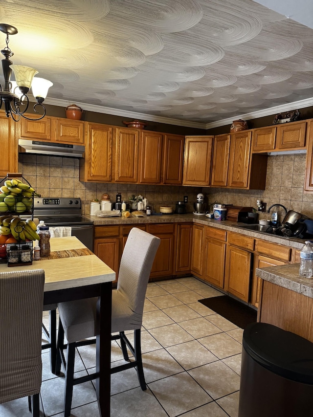 kitchen with a notable chandelier, brown cabinets, stainless steel range with electric stovetop, and under cabinet range hood