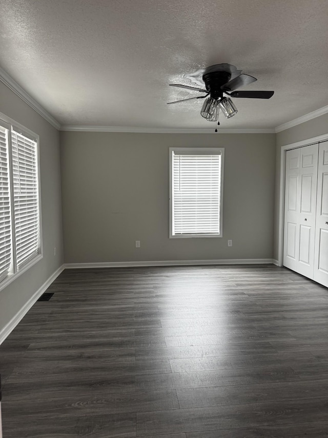 unfurnished bedroom featuring baseboards, a textured ceiling, ornamental molding, and dark wood-type flooring