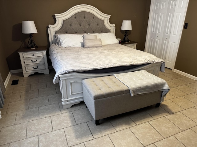 bedroom with a closet, tile patterned floors, and baseboards