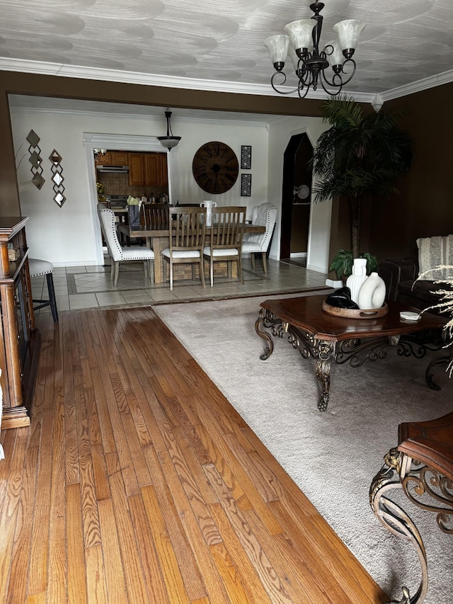 living room with a chandelier, ornamental molding, arched walkways, and wood finished floors