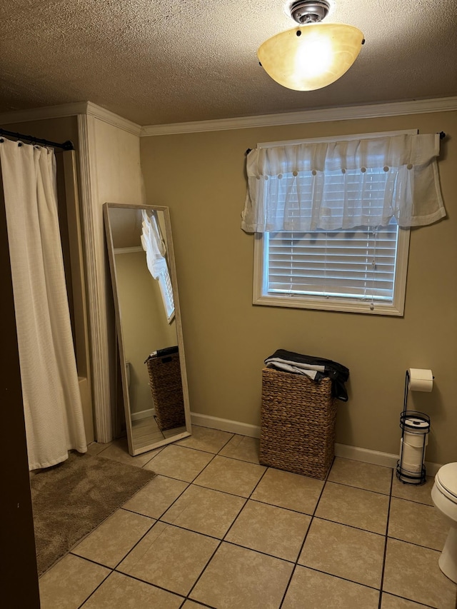 bathroom with a textured ceiling, tile patterned flooring, toilet, and crown molding