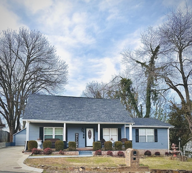 view of front of home featuring a porch, a front yard, an outdoor structure, and a shingled roof