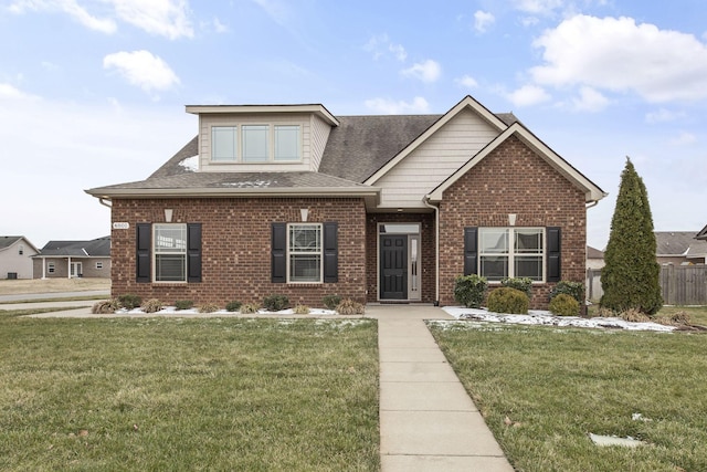 view of front of property with a shingled roof, brick siding, and a front lawn