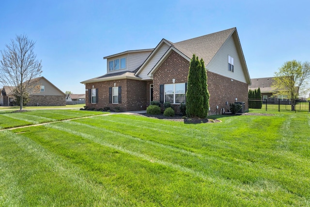 view of side of property featuring a yard, brick siding, and fence
