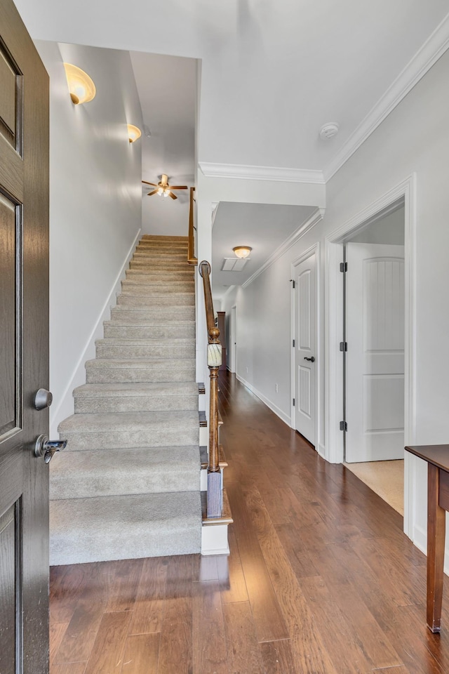 stairs featuring crown molding, ceiling fan, wood finished floors, and baseboards