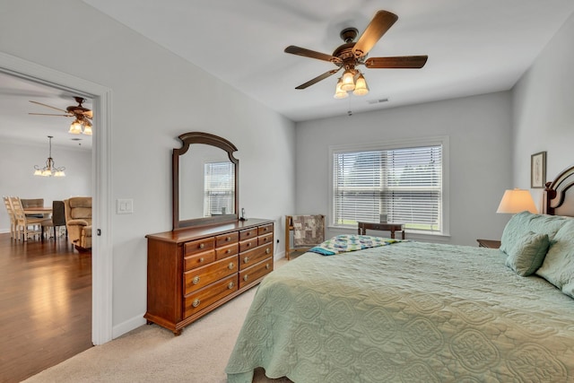 bedroom with baseboards, light colored carpet, and ceiling fan with notable chandelier