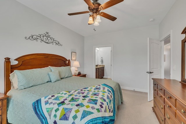 bedroom featuring light carpet, ceiling fan, baseboards, and ensuite bath