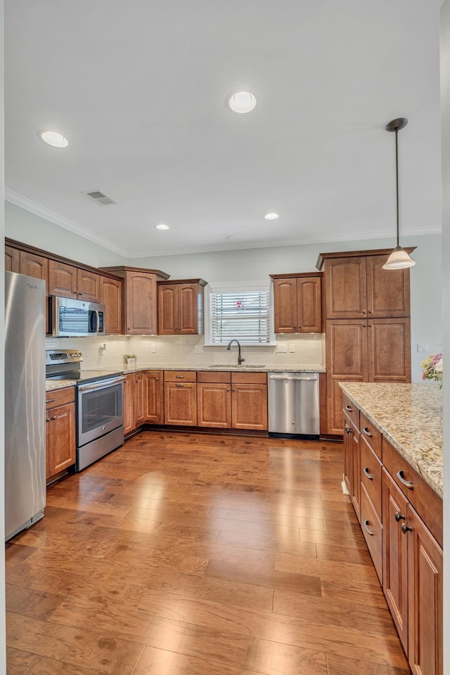 kitchen with stainless steel appliances, brown cabinetry, visible vents, and a sink