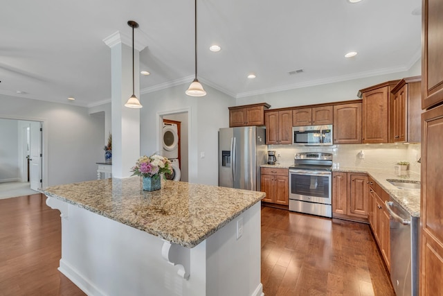 kitchen featuring light stone countertops, a breakfast bar, appliances with stainless steel finishes, stacked washer and clothes dryer, and dark wood-style floors